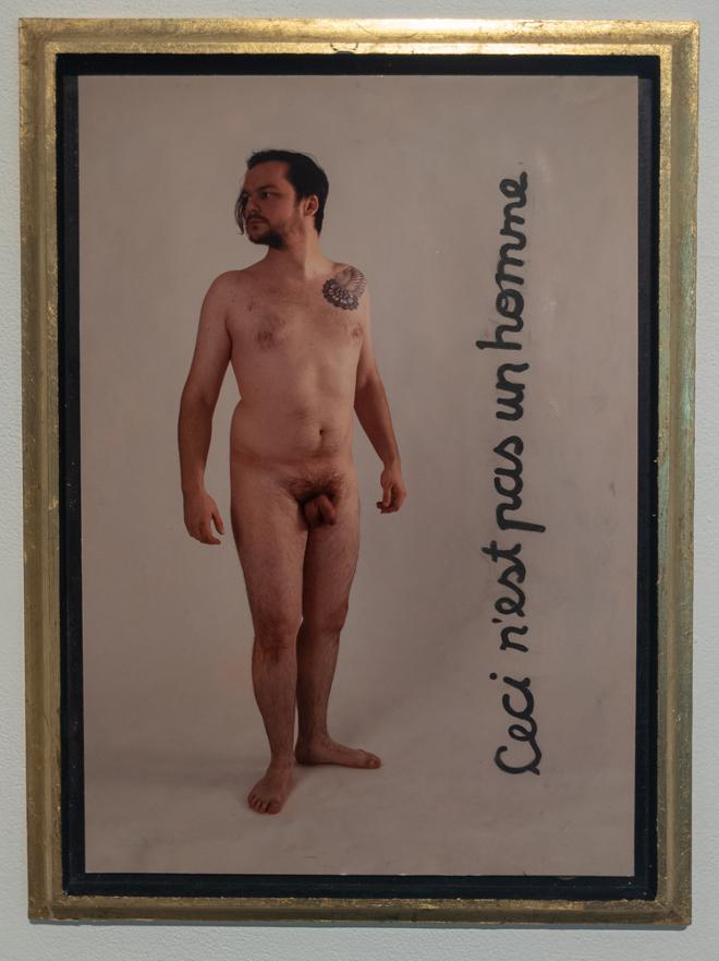 Photo of a nude with gold frame and the text, Ceci nest pas un home.