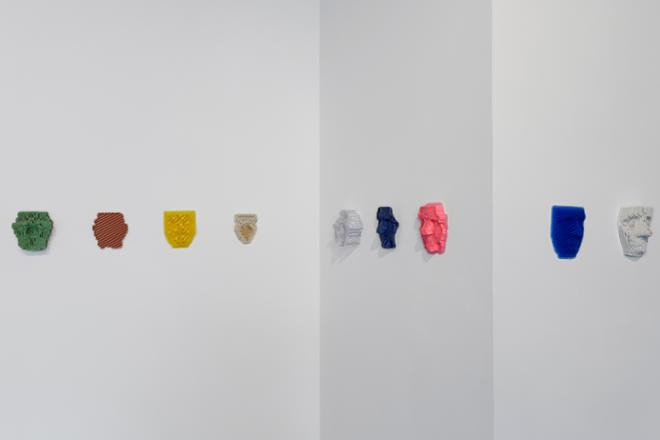 Nine colorful masks in a variety of colors are hung on the wall wrapping the corner of the gallery. The masks are hung at the artist’s height, and represent multiple techniques used in her studio practice. 