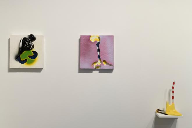 Two surreal wall mounted tiles, and one small sculpture sits on a shelf. All pieces were hand-made using artificial intelligence source imagery. 