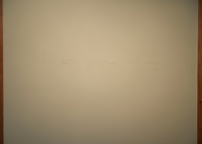 A close up of spackle built up in the form of handwriting that reads “I’m sorry you feel that way”