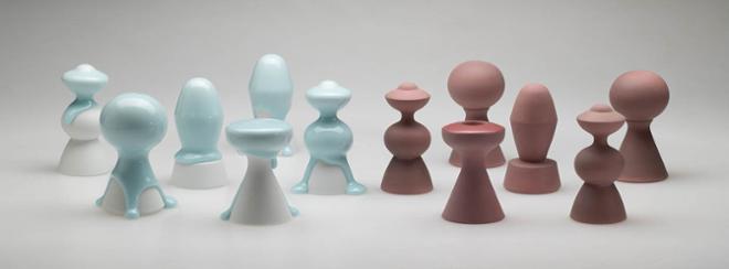 an arrangement of items in two, long rows. The items to the left are white with light blue glaze dripping down. The items to the right are a matte maroon color. 