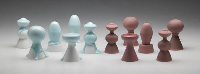 an arrangement of items in two, long rows. The items to the left are white with light blue glaze dripping down. The items to the right are a matte maroon color.  