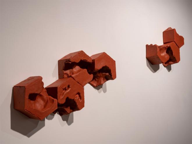 Hexagonal blocks are arranged into small groups and packed on the wall.  This is a small installation that includes 7 block shapes total
