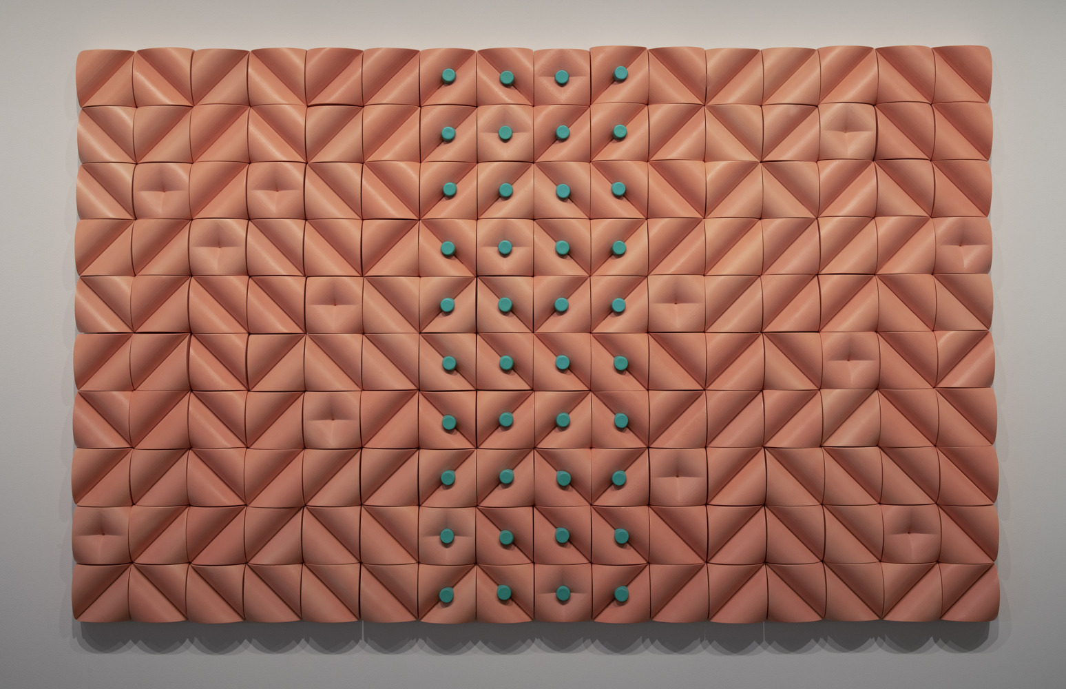 a large, pink, rectangular tile piece of a geometric design featuring green dots in the middle