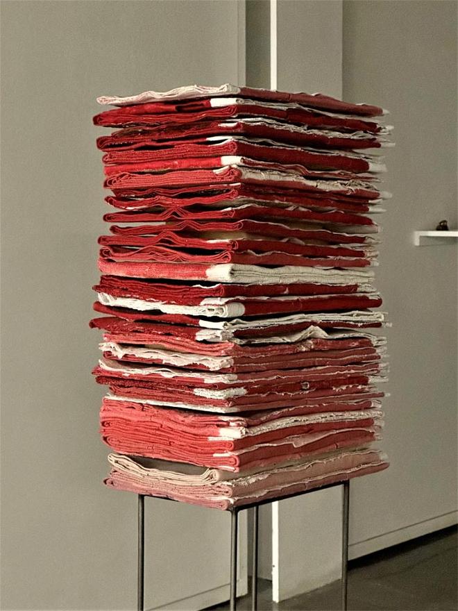 Red fabric-like sculpture stacked on top of each other on a stand.