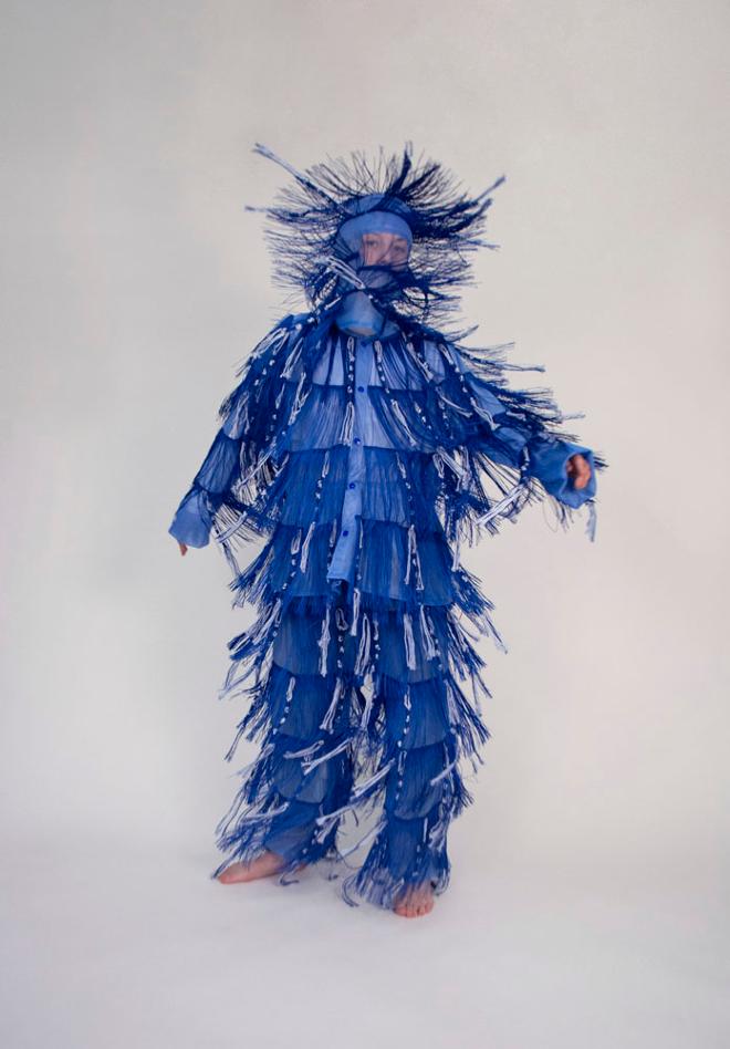 A figure wearing a blue garment covered in blue fringe.