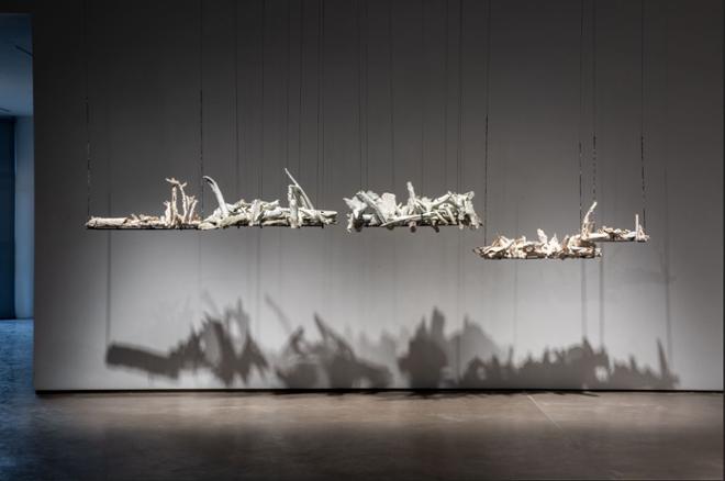 Installation image of a white branchy sculptures suspended in the air. They are held up by metal. 