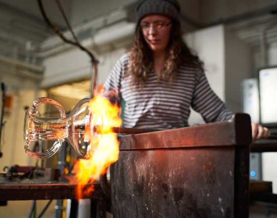 Student blowing a glass vase in the hot shop