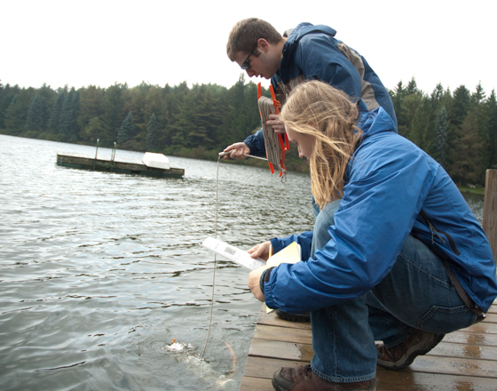 Students conducting an experiment using a meter in the water at Foster Lake