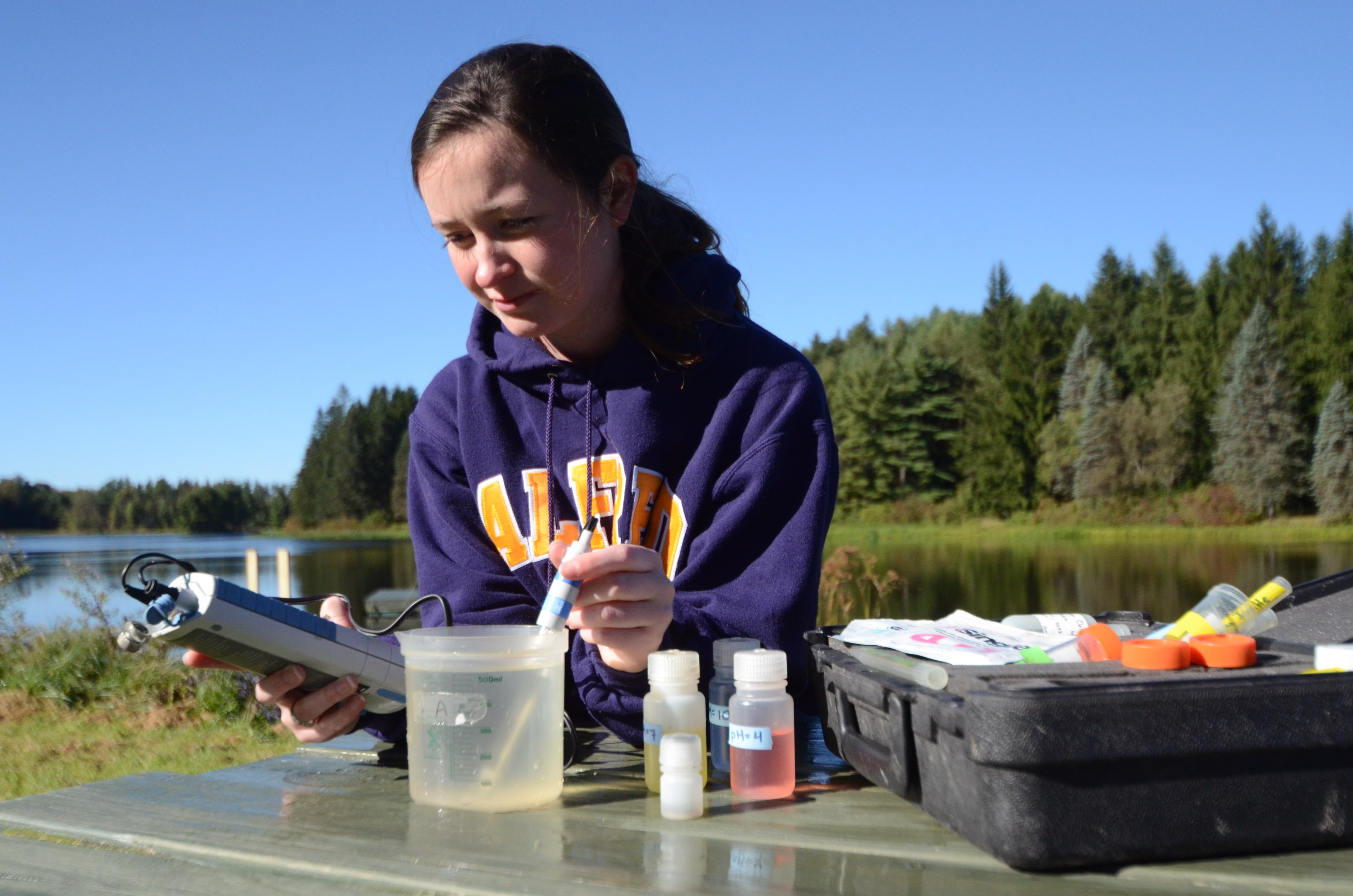 Student testing the pH of water using a meter at Foster Lake