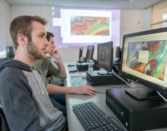 Student working at a computer with GIS software data on the screen