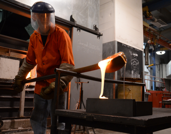 Student pouring molten glass into a mold