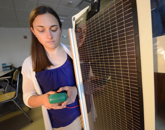 Student working on a solar panel holding a multimeter