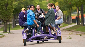 Students riding bike down academic alley. 