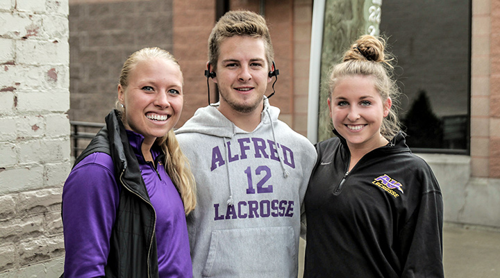 three students smiling together in saxon athletic clothing