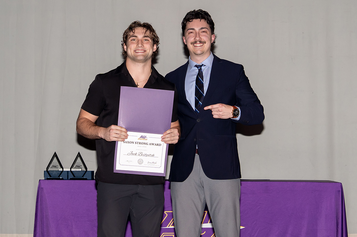A photo of two Alfred University students smiling and holding an award