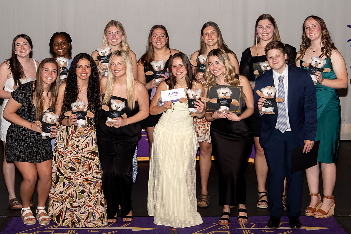 A photo of many Alfred University students smiling and holding an award