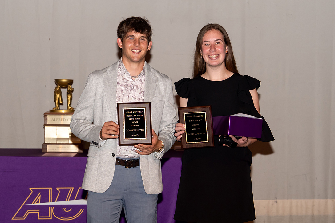 A photo of two Alfred University students smiling and holding an award