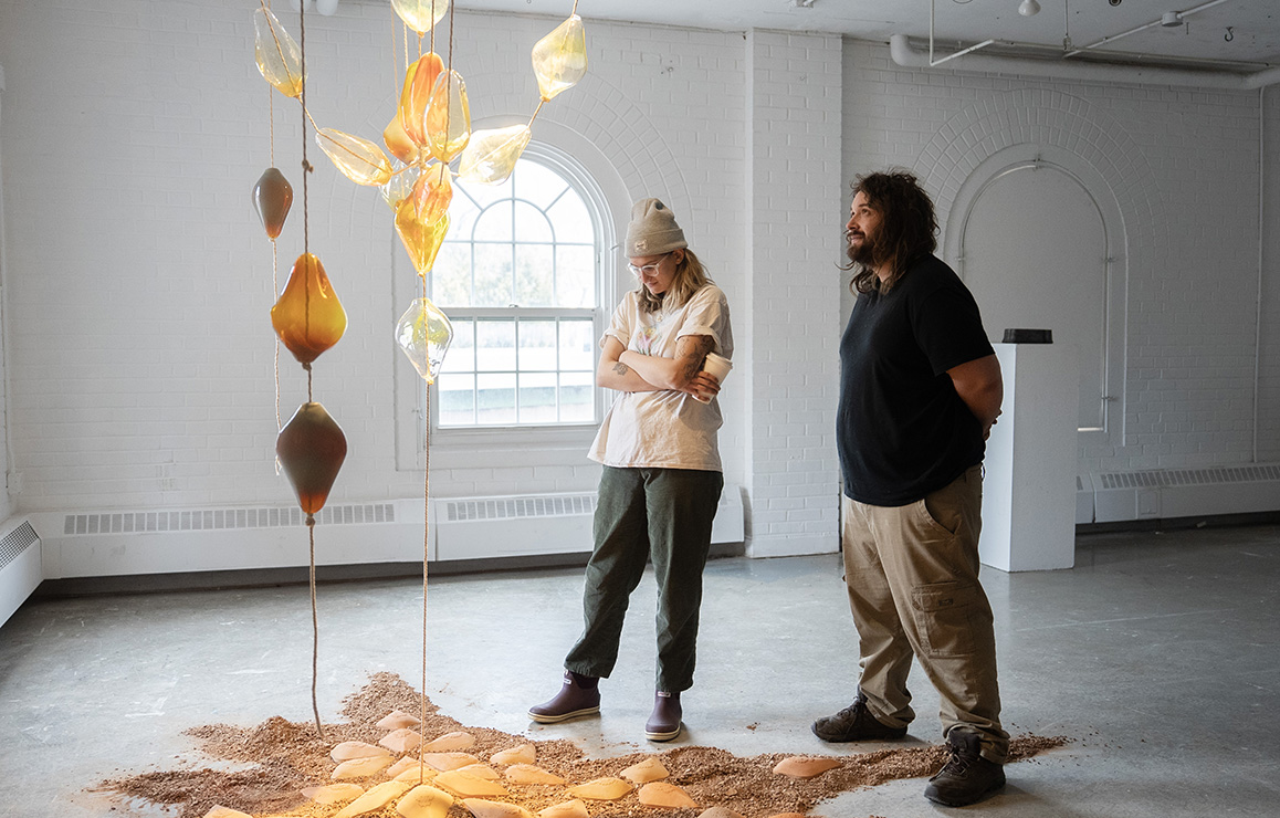 A photo of an Alfred University student admiring artwork on display