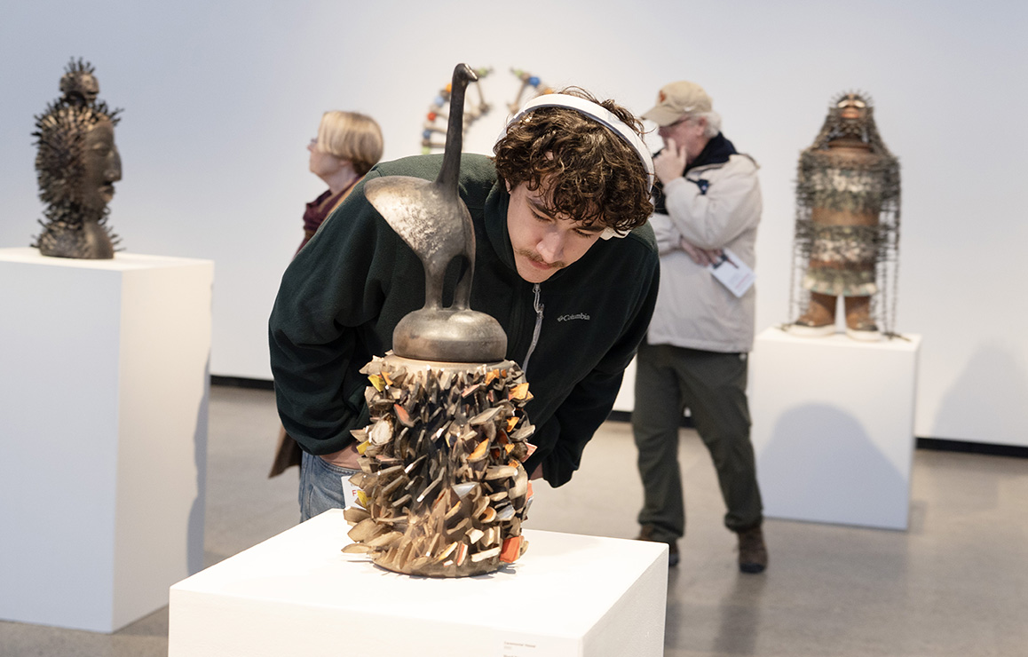 A photo of an Alfred University student admiring artwork on display