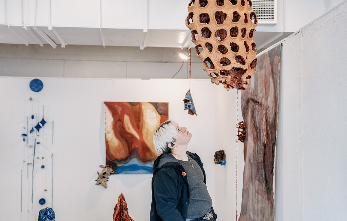 A photo of an Alfred University student admiring artwork on display