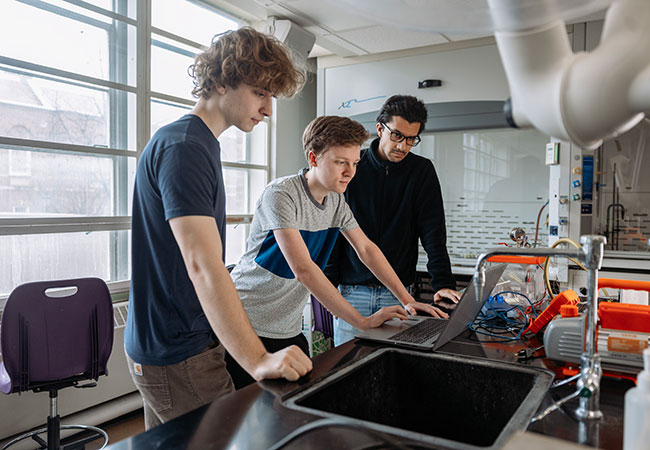 A photo of three mechanical engineering students working in an engineering lab