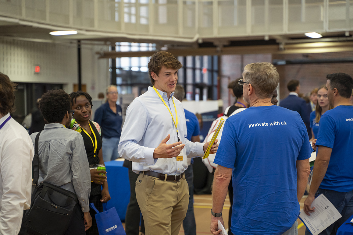 An Alfred University student speaks with an employer wearing a blue ‘Innovate with us’ shirt at the campus Career Fair.