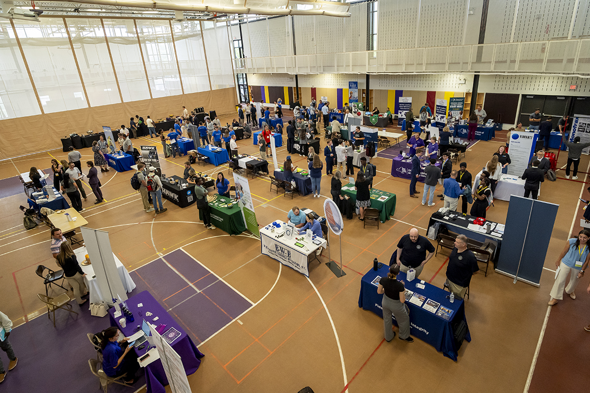 Overhead view of the Alfred University Career Fair with students and employers interacting at tables set up in the gymnasium.