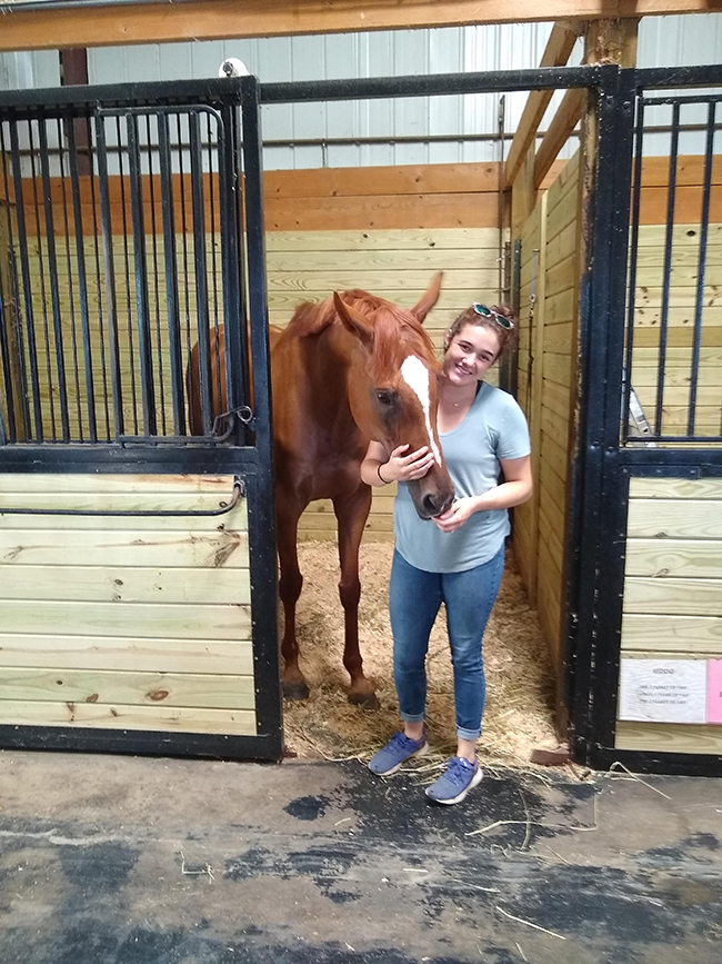A photo of Emma Johnson in a horse stall