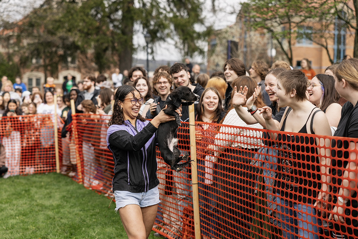 A photo of a student holding up a wiener dog during Hot Dog Day