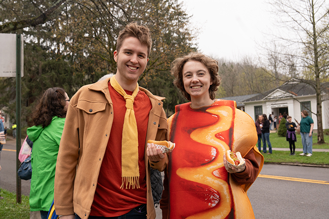 A photo of two Alfred University students in hot dog costumes eating hot dogs