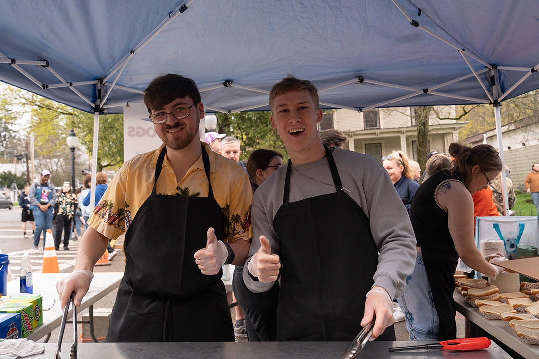 A photo of two Alfred University students cooking hot dogs