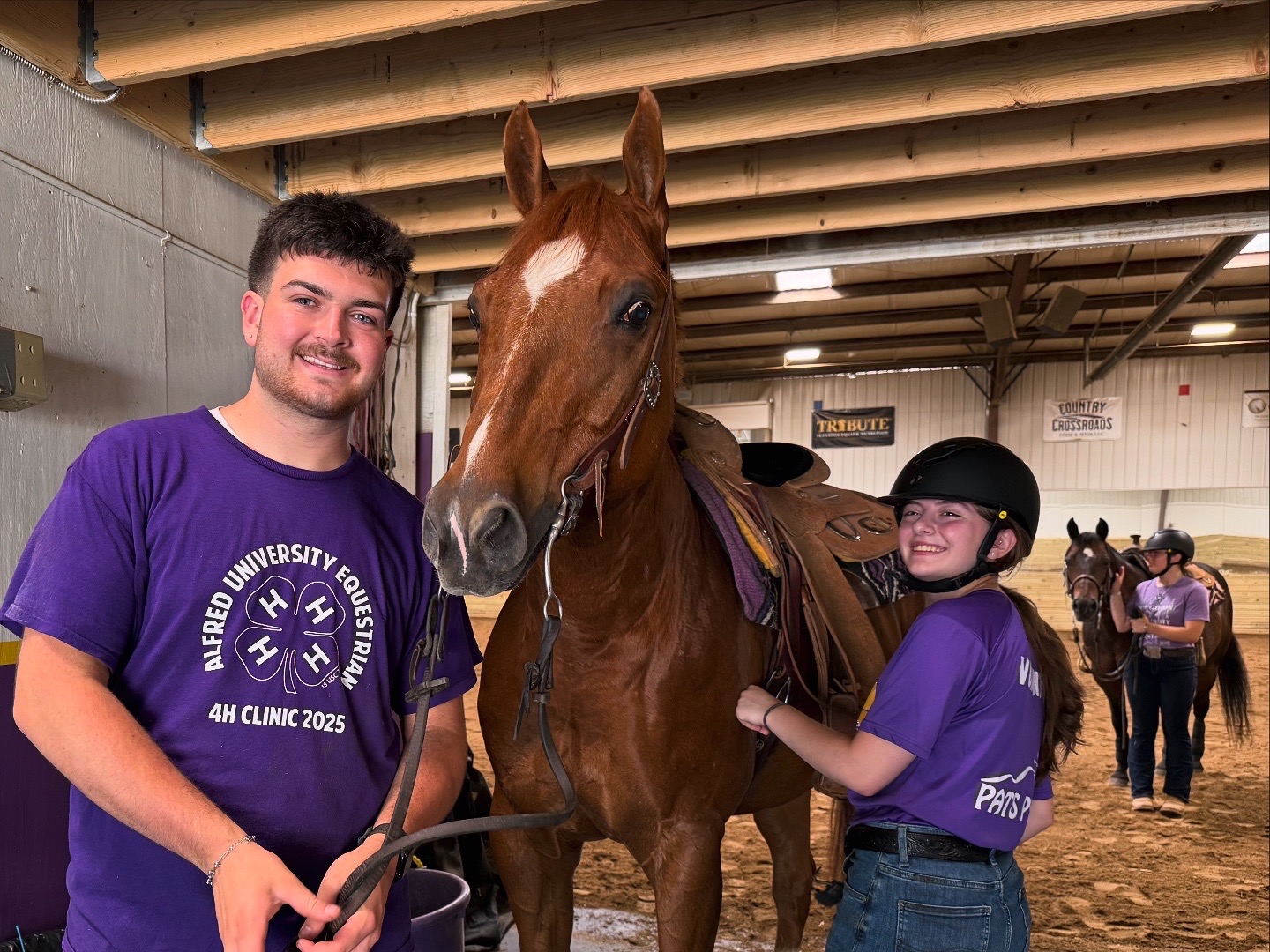A photo of two Alfred University students with a brown horse