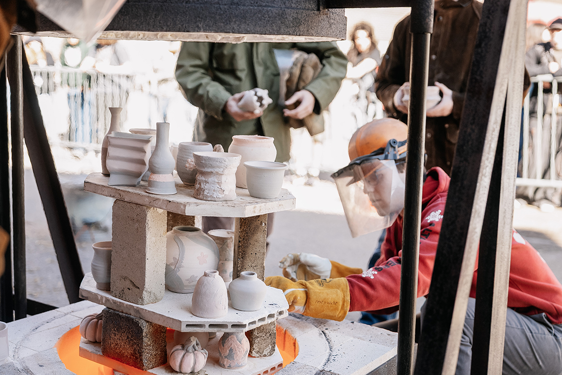 A photo of an Alfred University student placing ceramic pots on stone