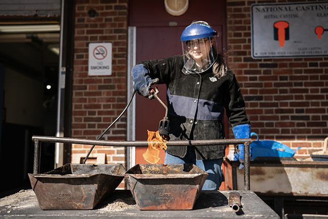 A photo of a woman using a tool with an open flame