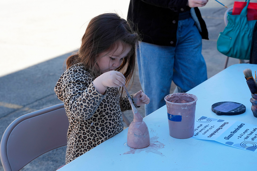 A photo of a child painting a ceramic cup