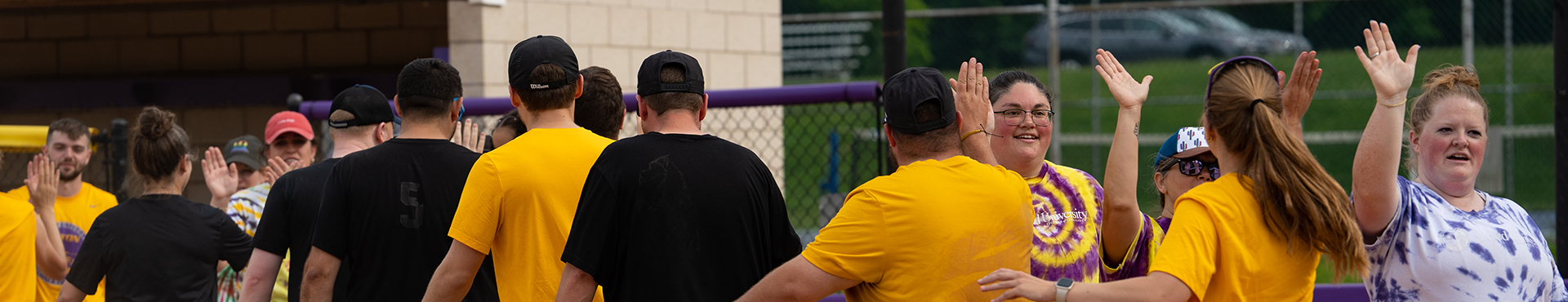 A photo of Alfred University faculty and staff high-fiving each other after a softball game