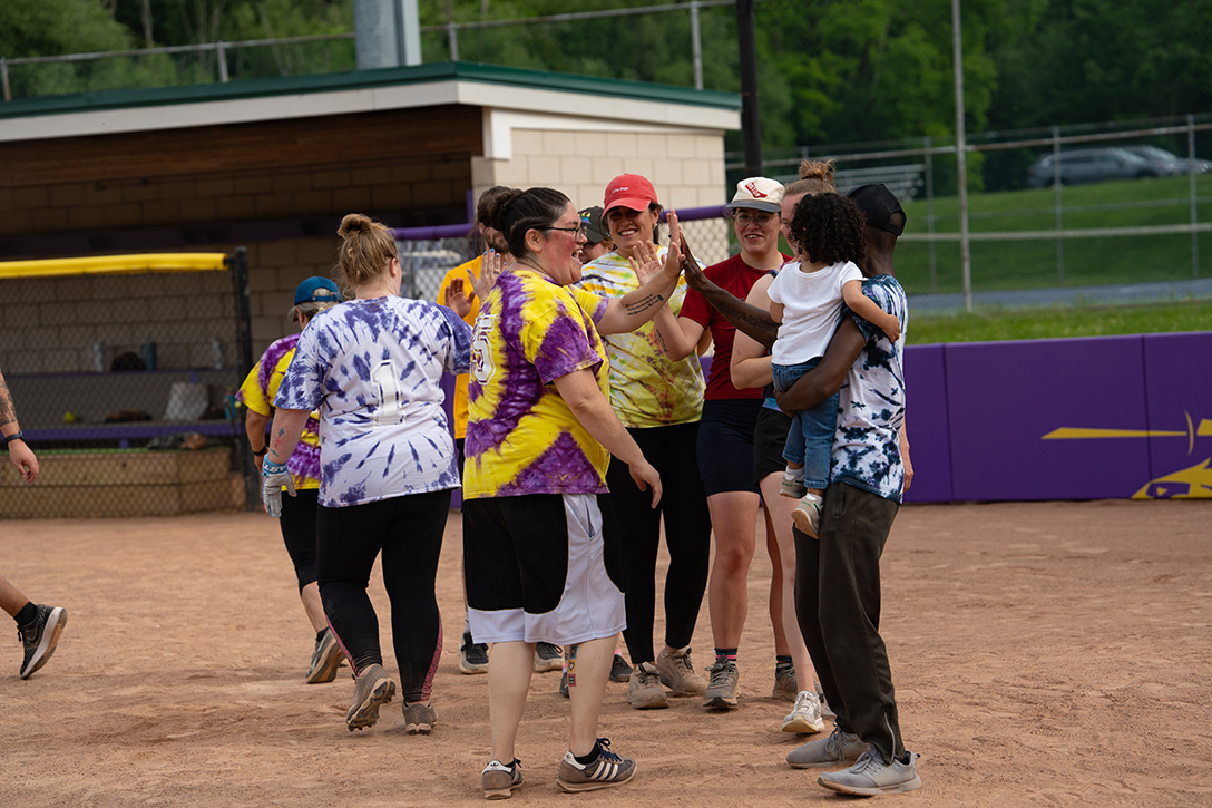 A photo of Alfred University faculty and staff high-fiving each other after a softball game