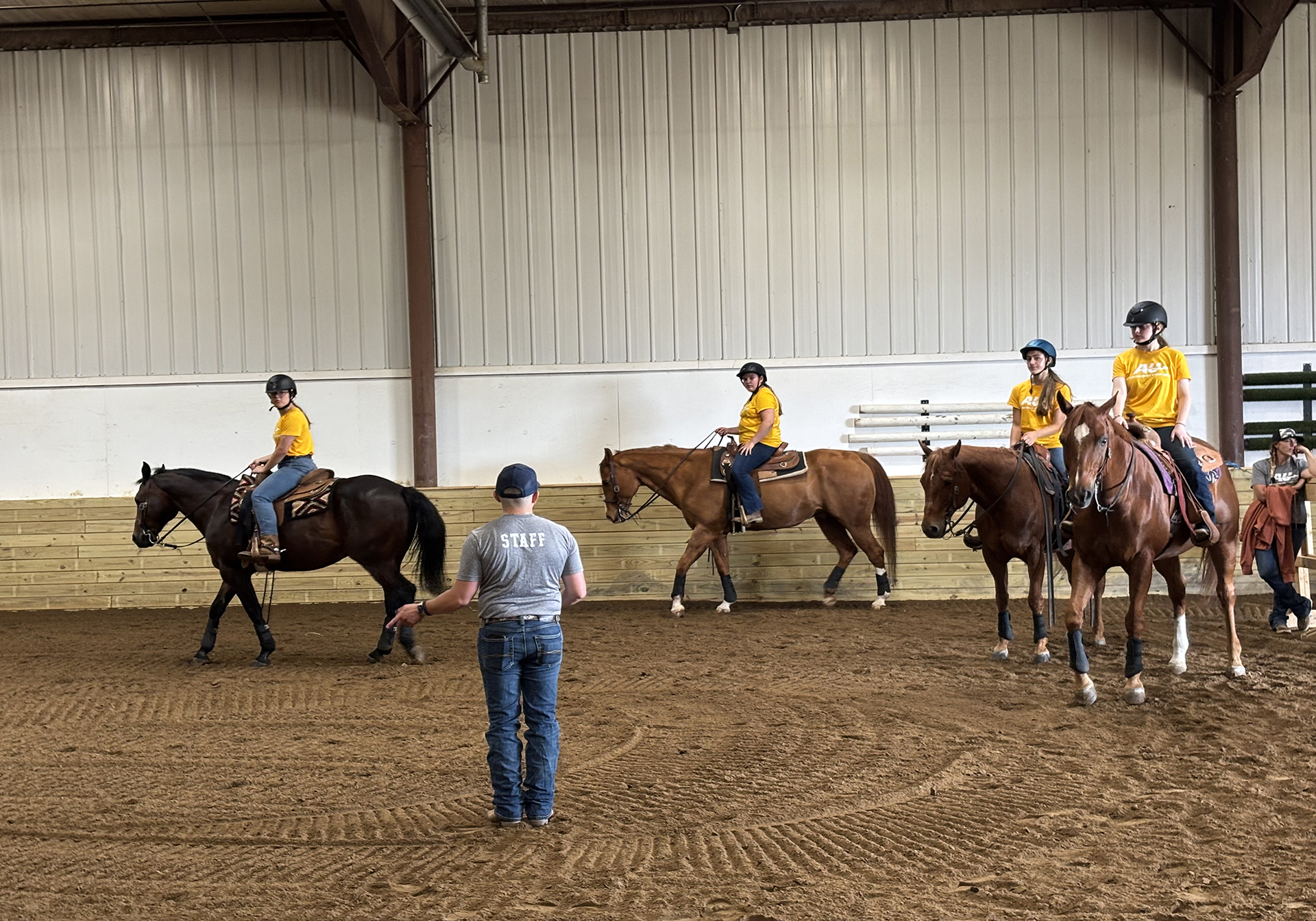 A photo of high school students riding horses led by an equestrian coach