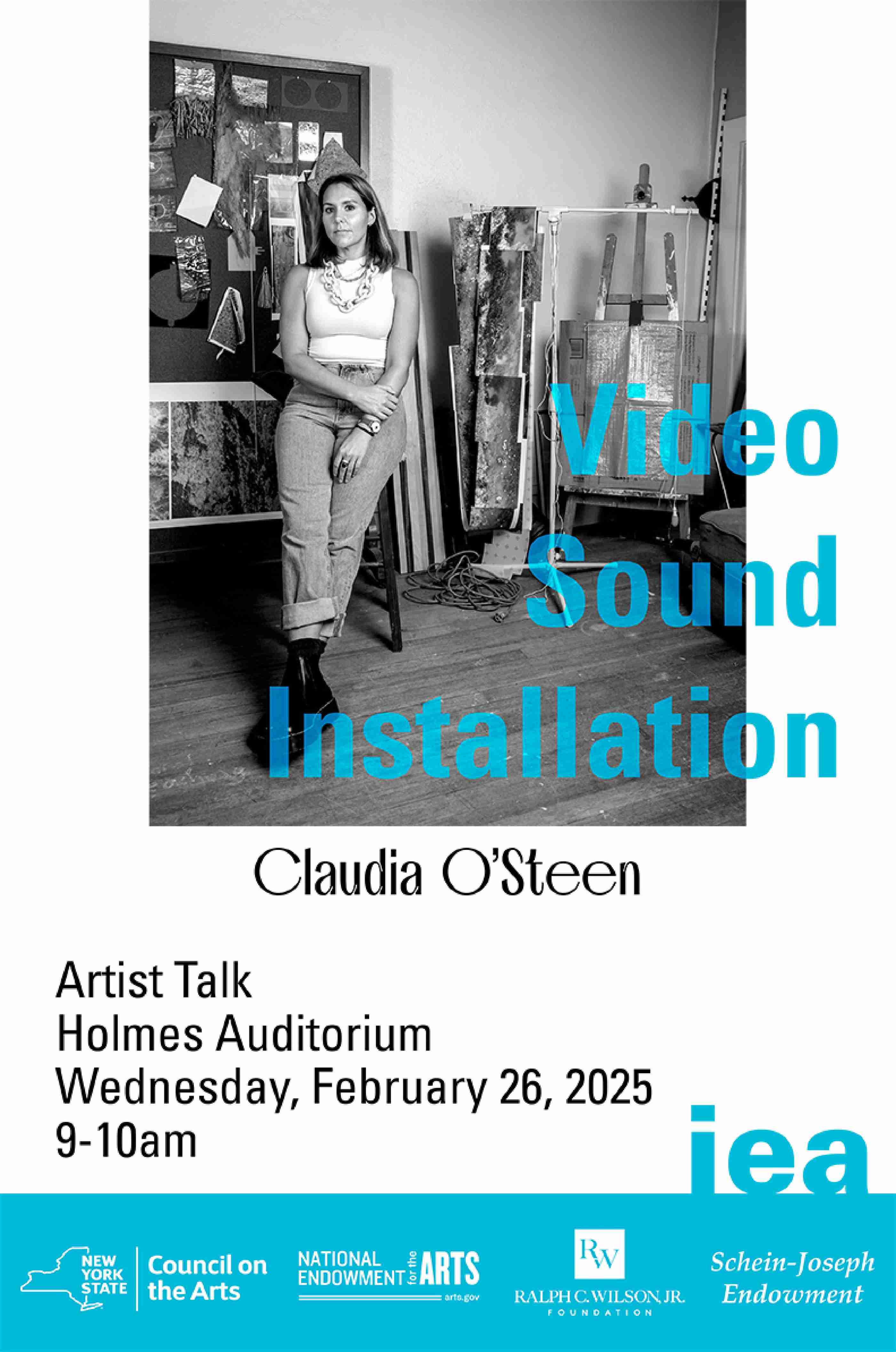 female artist stands, posing in her art studio against a backdrop of artworks in-progress