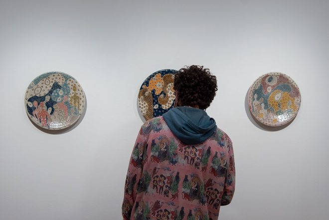 back of person looking at three patterned plates hung on the wall
