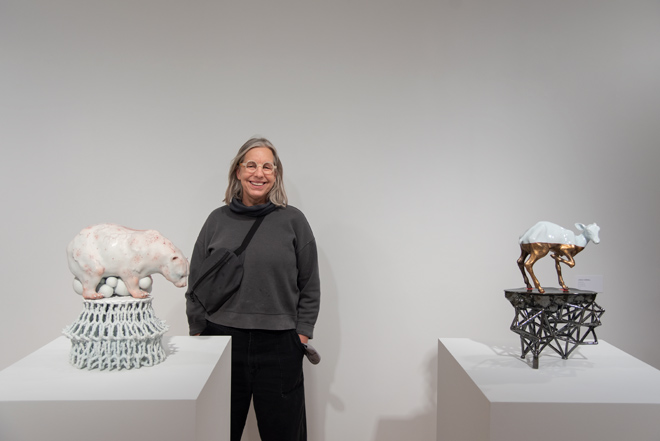 Linda posing next to animal themed ceramic pieces