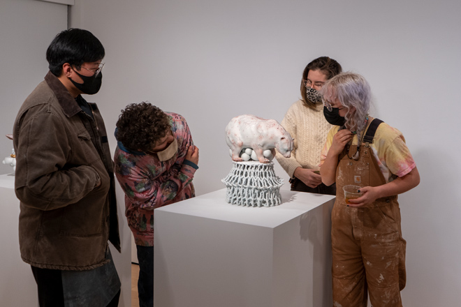 people viewing ceramic piece featuring a bear