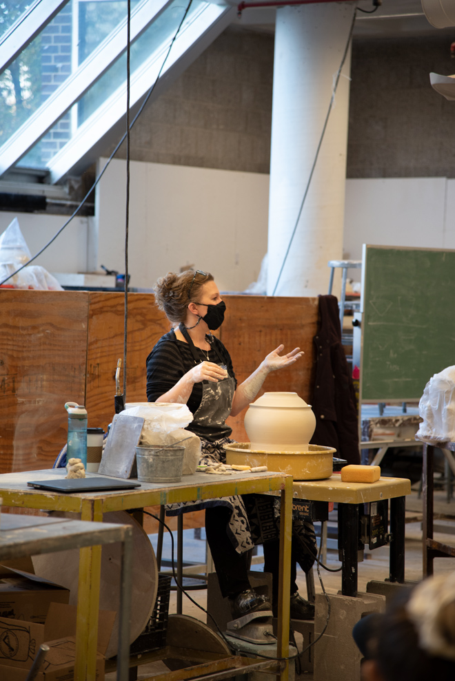 person talking while working with ceramic piece
