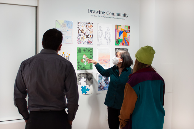 Sharon McConnell pointing to artwork while talking to a small group of people