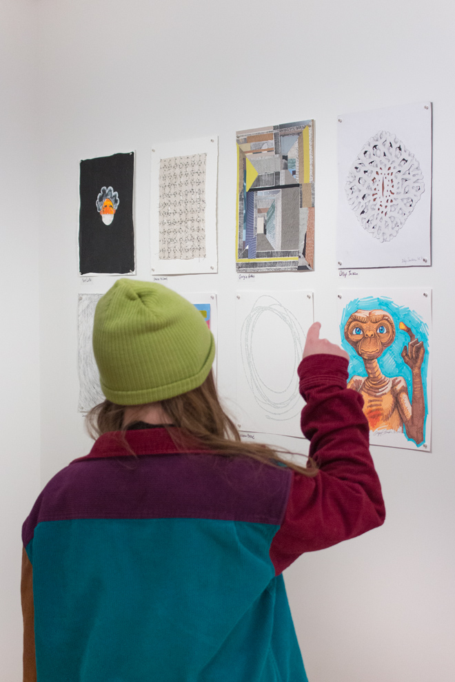 person pointing like the drawing of E.T. character in one of the pieces displayed