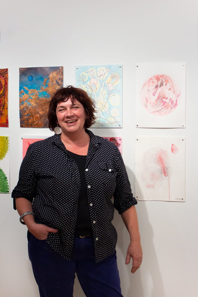 a smiling Coral Lambert posing in front of drawings