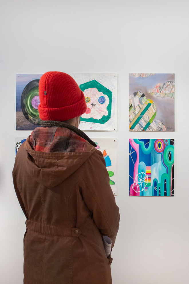 Person in red hat looking at drawings on display