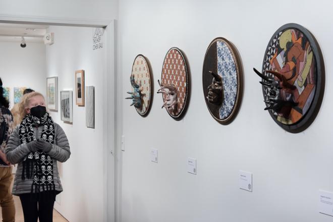 people looking at series of circular 3-D plate pieces hung on the wall