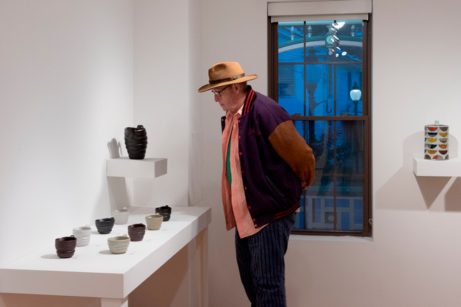 person looking closely at some of the pottery on display